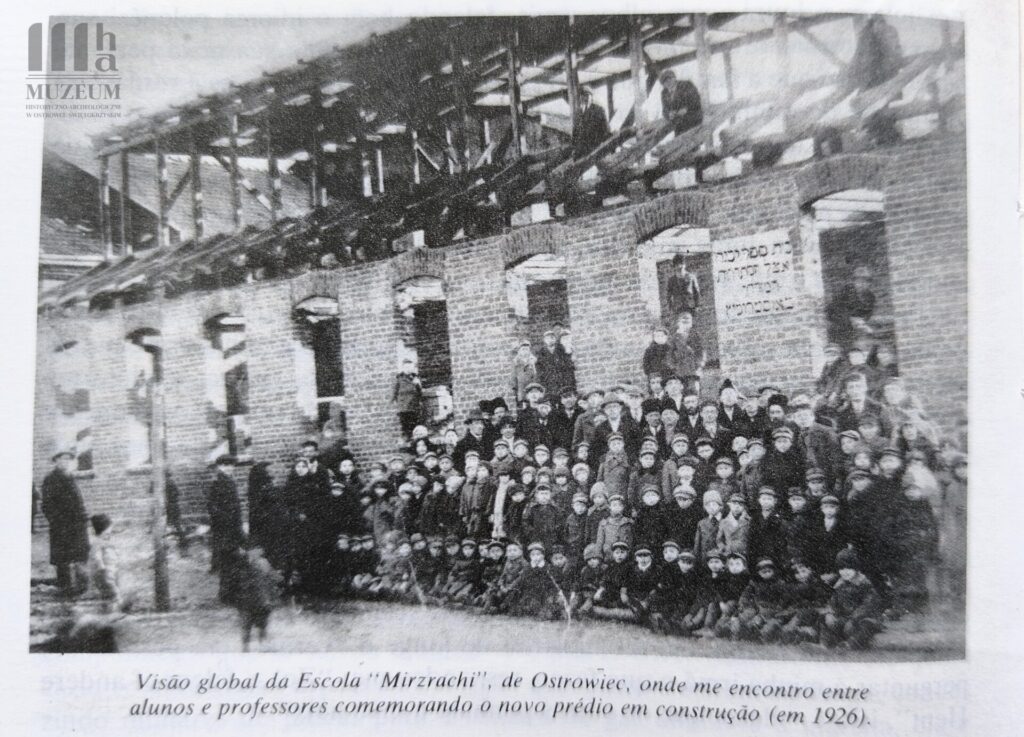 Grupa uczniów i nauczycieli przed powstającym budynkiem szkoły